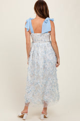 woman wearing a light blue floral midi dress with a smocked bodice and tie shoulder straps, seen from the back