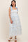 woman wearing a light blue floral maternity dress with ruffled layers and bow-tie straps, showcasing her baby bump