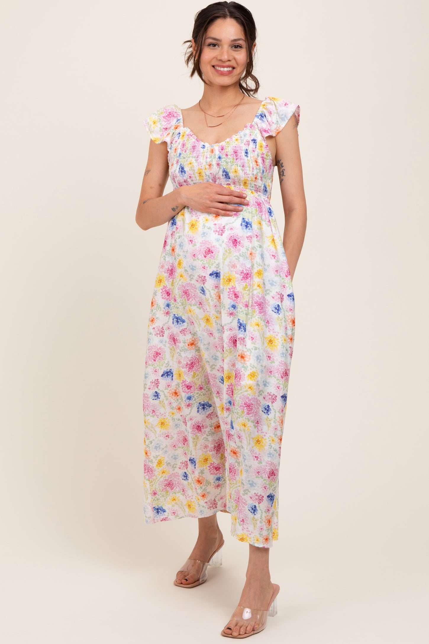 woman wearing a white floral print maternity dress with flutter sleeves and a visible baby bump