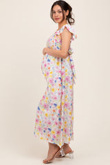 woman wearing a floral print maternity maxi dress with ruffle sleeves and holding her baby bump