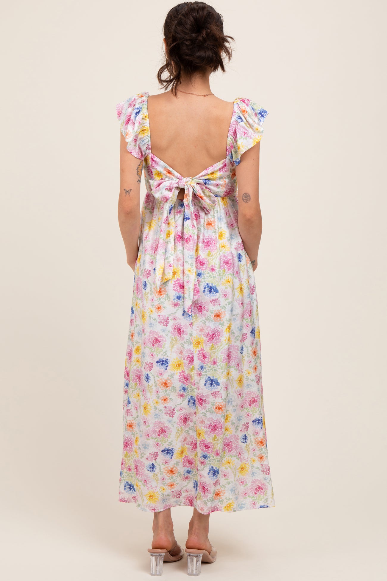 woman wearing a floral print maternity maxi dress with a tied back and ruffled sleeves