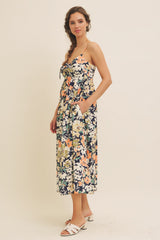 woman wearing a floral midi dress with a tied front and pockets, paired with white sandals