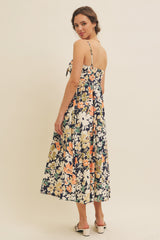 woman wearing a navy blue floral midi dress with adjustable straps and a tie at the back