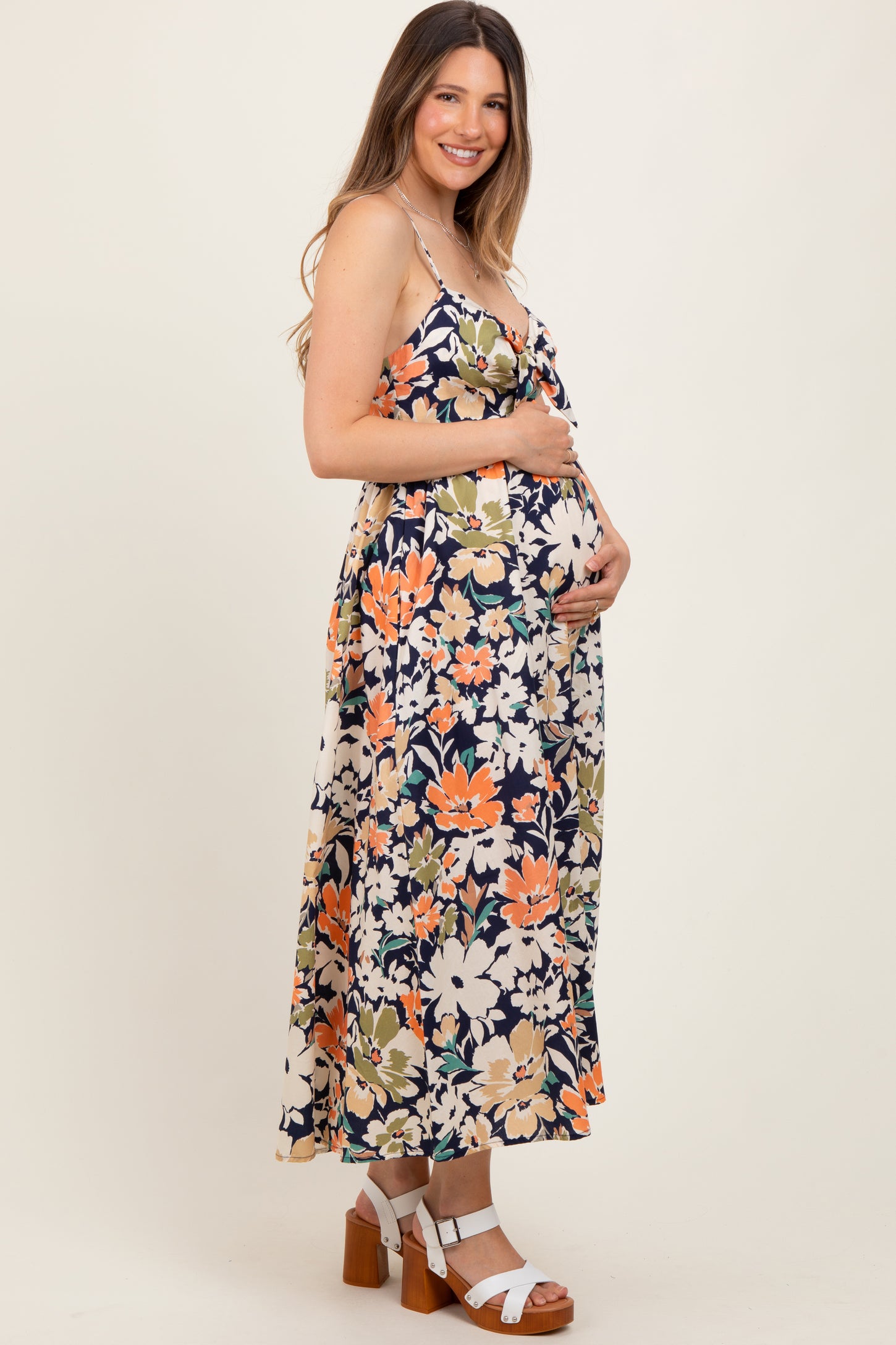 woman wearing a floral maternity maxi dress and cradling her baby bump