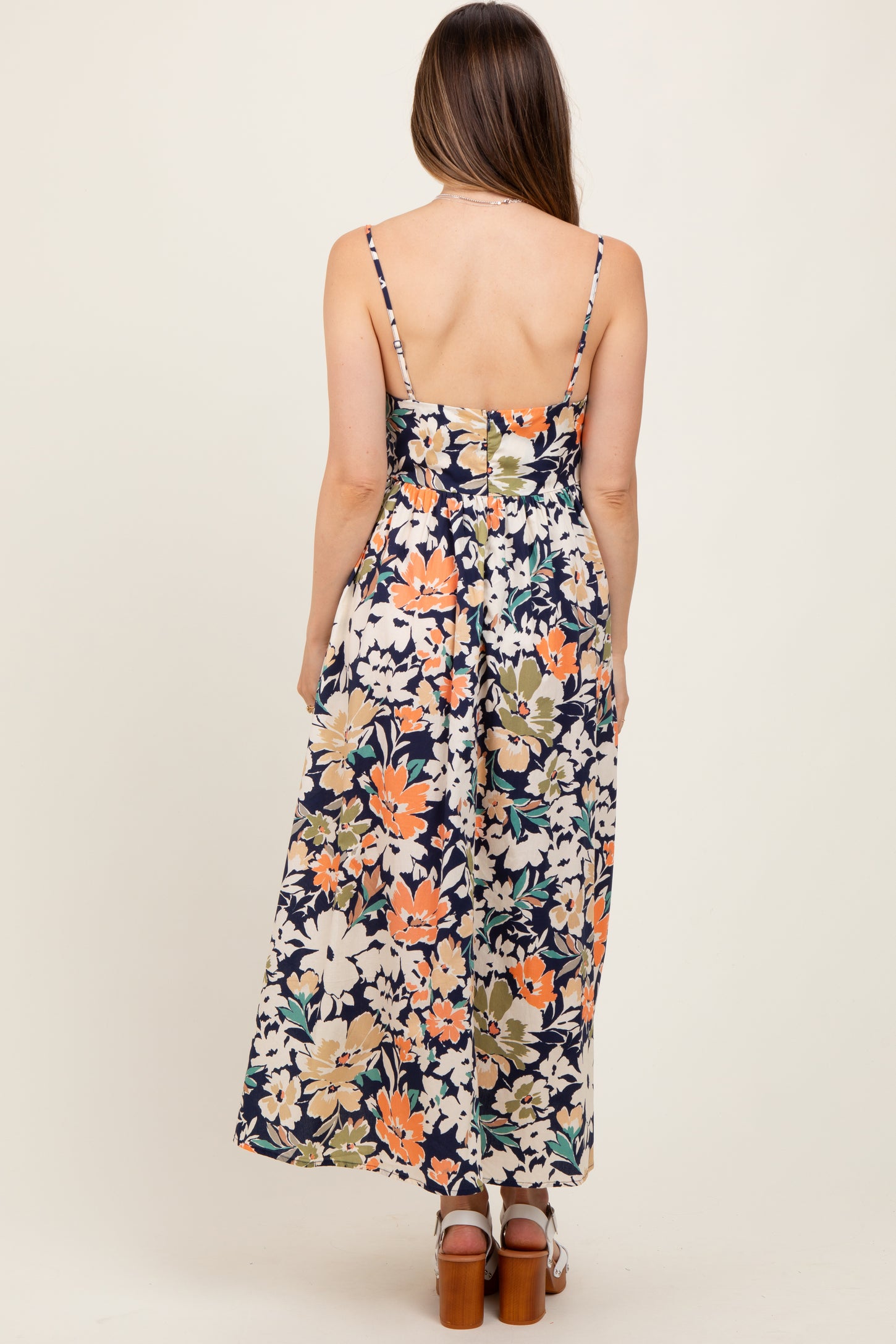 woman wearing a floral maternity maxi dress with a fitted bodice and adjustable straps, viewed from the back