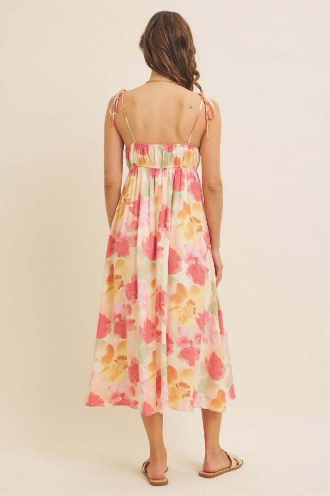 woman wearing a floral maxi dress with adjustable straps and a smocked back, viewed from the back