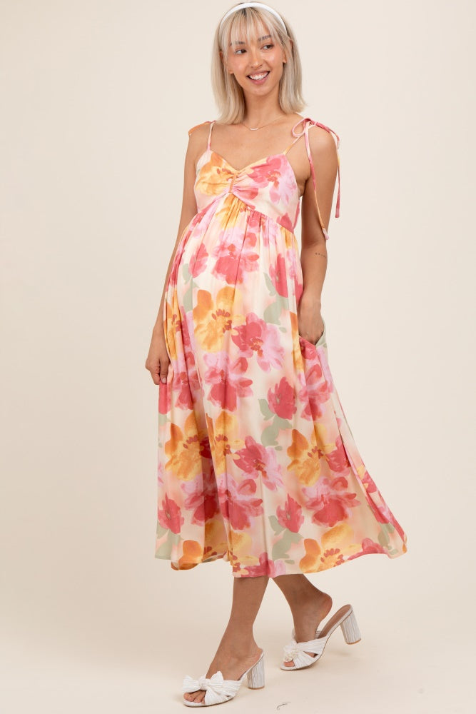 woman wearing a floral maternity dress with adjustable straps and a flowy hem, showing her baby bump