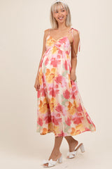 woman wearing a floral maternity dress with adjustable straps and a flowy hem, showing her baby bump