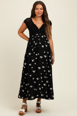 woman wearing a black floral maternity maxi dress with a knitted top and a visible baby bump