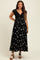 woman wearing a black floral maternity maxi dress with a knitted top and a visible baby bump