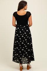 woman wearing a black floral maternity maxi dress with a knit top and a flowing skirt, showing a baby bump from behind