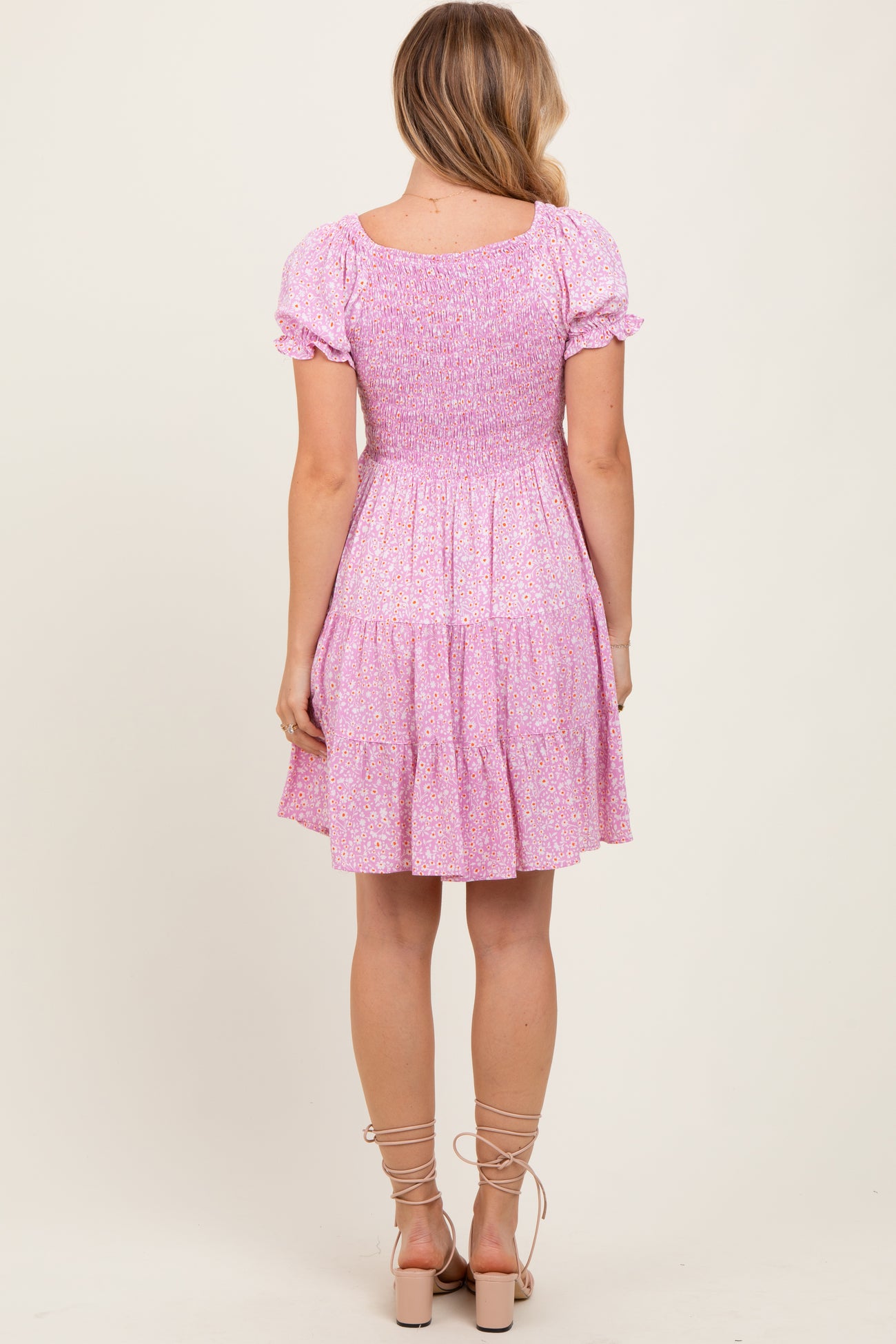 woman wearing a pink floral smocked mini dress with short puff sleeves and a tiered skirt