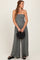 woman wearing a gray strapless jumpsuit and holding a black woven handbag