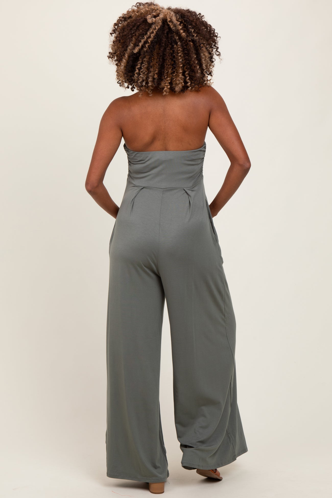 woman wearing a green strapless maternity jumpsuit with wide leg pants, shown from the back
