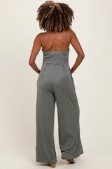 woman wearing a green strapless maternity jumpsuit with wide leg pants, shown from the back