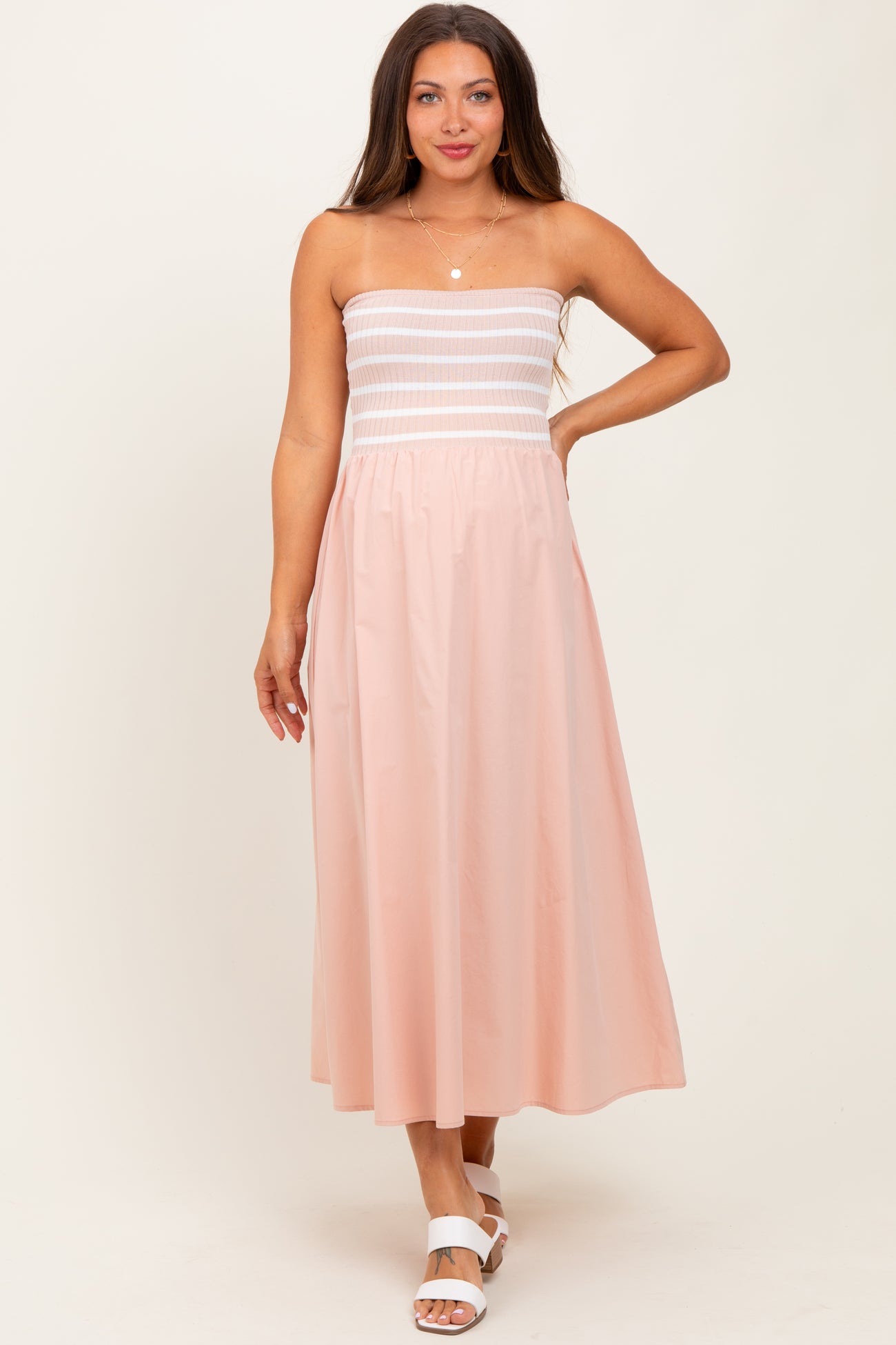 woman wearing a strapless pink maternity maxi dress with a fitted bodice and flowy skirt