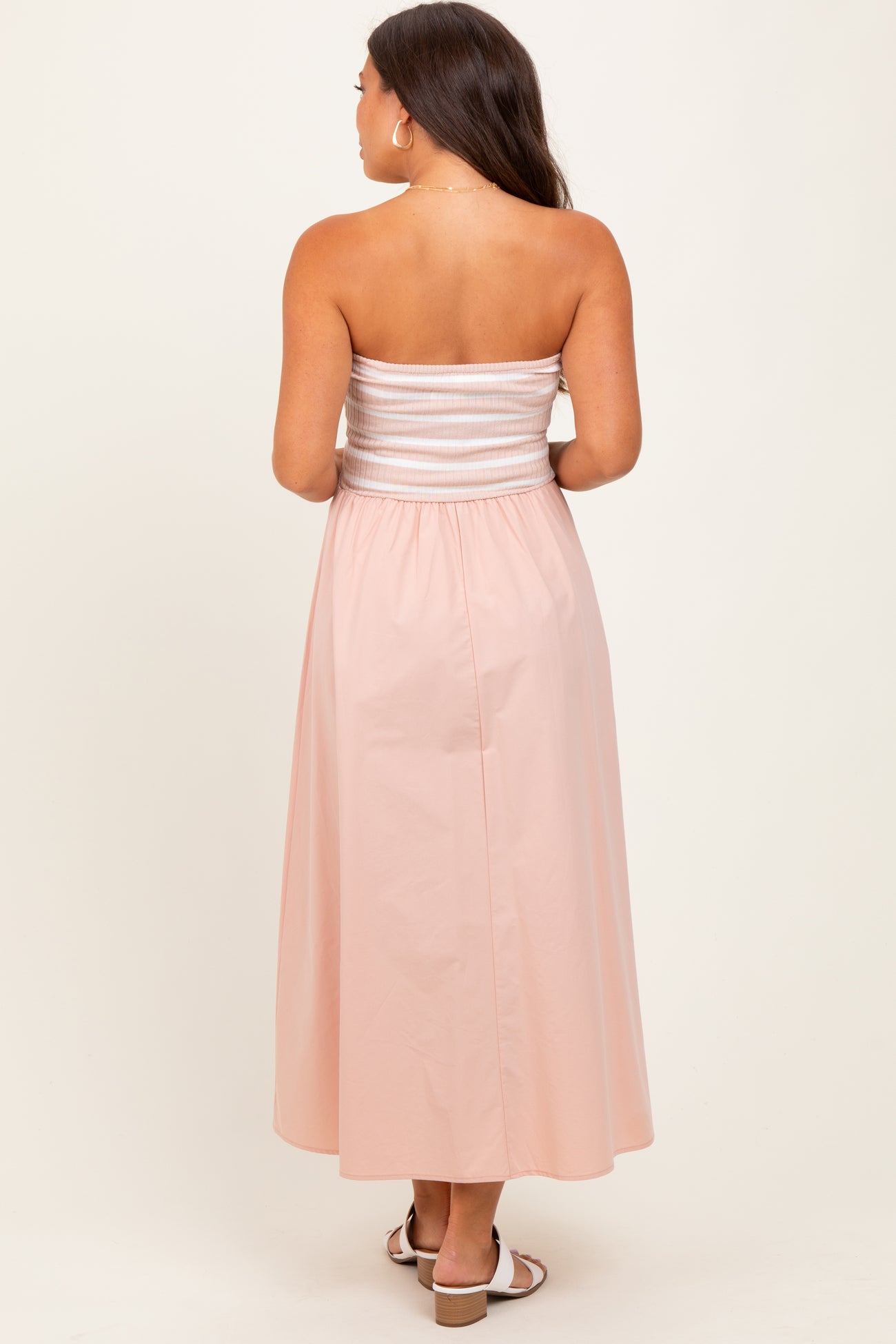 woman wearing a maternity pink strapless maxi dress with a smocked bodice and flowing skirt from the back