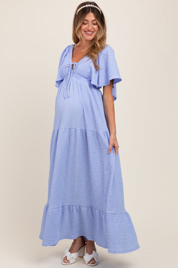 woman wearing a light blue maternity maxi dress with flutter sleeves and a tie at the bust, showcasing her baby bump