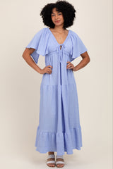 woman wearing a light blue maxi dress with puff sleeves and a tie front detail