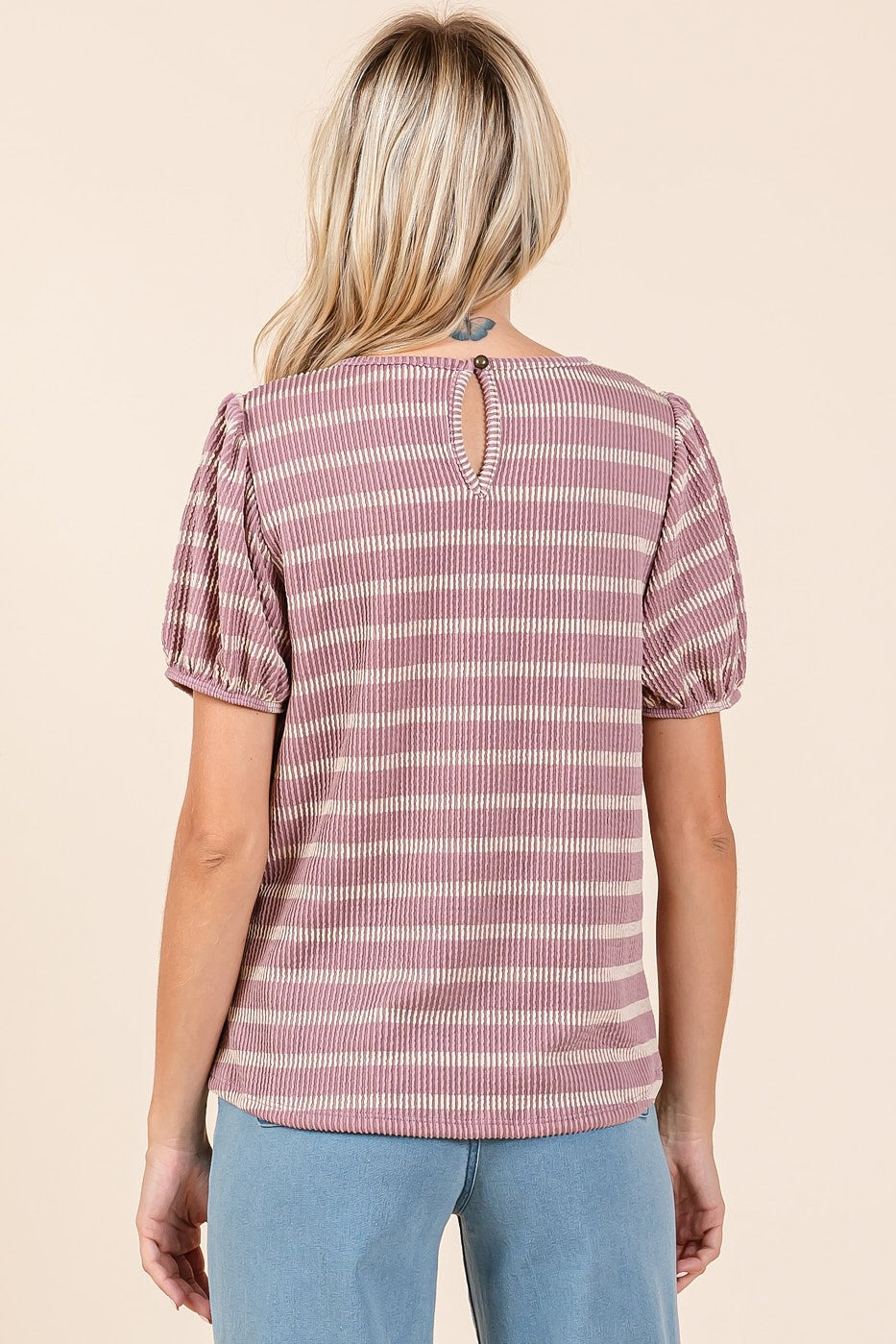woman wearing a pink and white striped short sleeve top with puff sleeves and a keyhole back detail