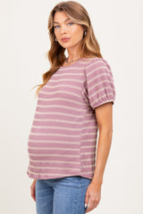 woman wearing a striped maternity top in shades of pink and cream, showcasing her baby bump with blue jeans