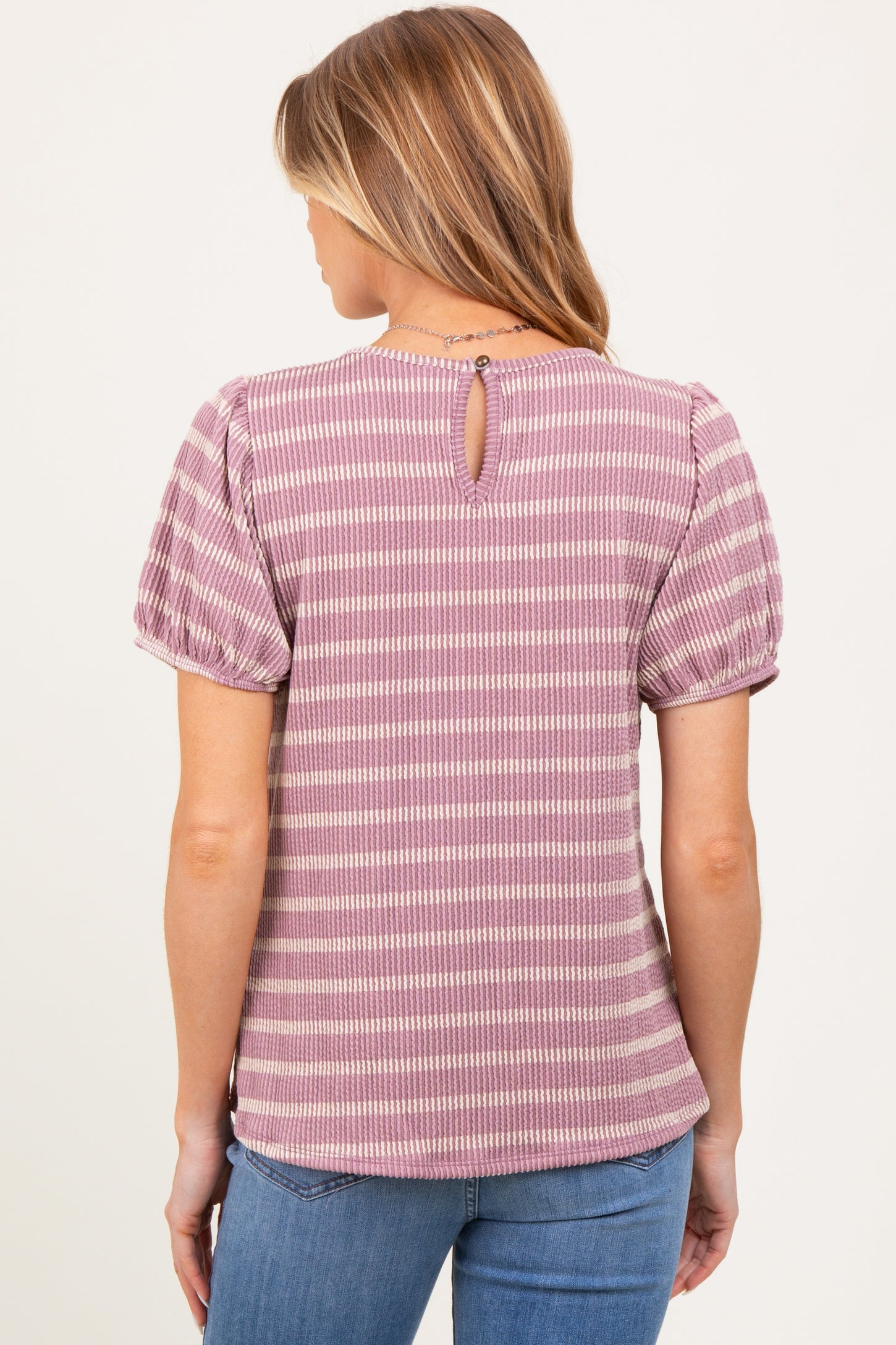 woman wearing a striped mauve maternity top with puff sleeves and a keyhole back detail