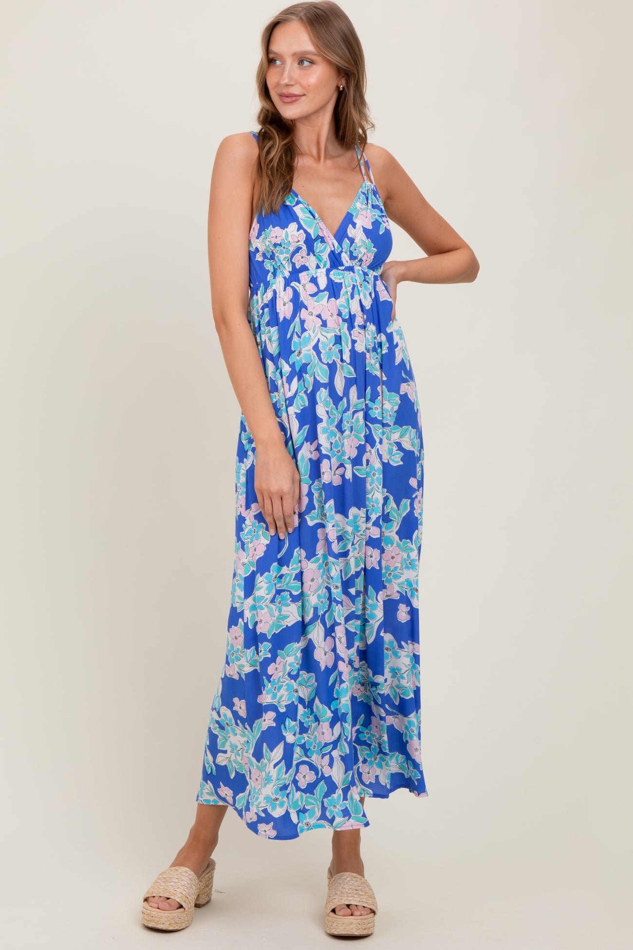 woman wearing a blue floral maxi dress with a deep V-neckline and spaghetti straps