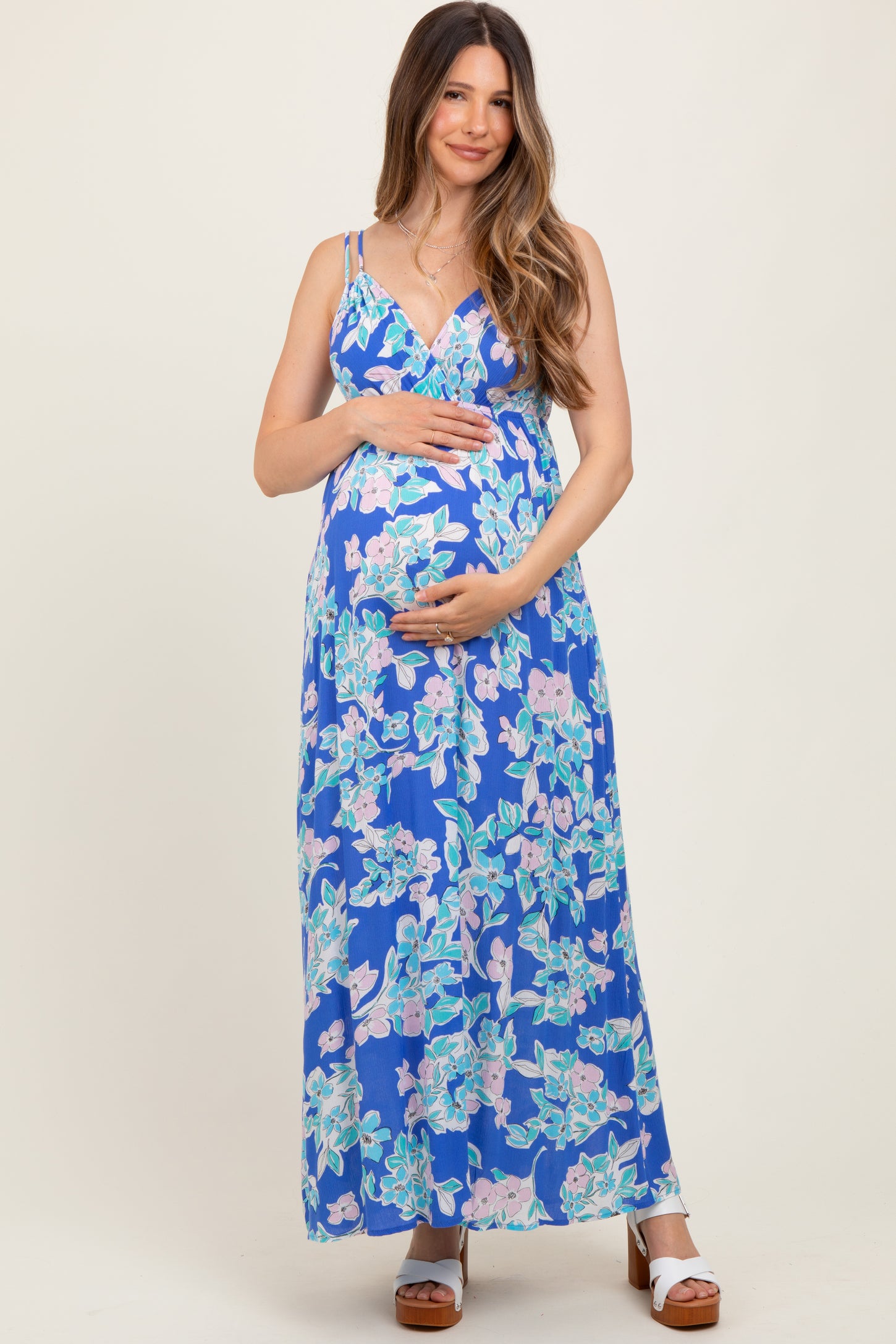 woman wearing a blue floral maternity maxi dress and holding her baby bump