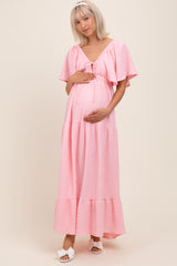 woman wearing a pink short sleeve maternity dress with a tie front and holding her baby bump