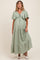 woman wearing a light green maternity maxi dress with flutter sleeves and a tiered hem, showing her baby bump