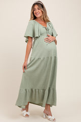 woman wearing a green tiered maternity maxi dress and holding her baby bump