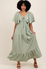 woman wearing a sage green tiered maxi dress with flutter sleeves and a tie front detail