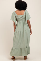 woman wearing a mint green maxi dress with short flutter sleeves and a tiered skirt, viewed from the back