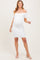woman wearing a white off-the-shoulder maternity dress, showing her baby bump, standing and smiling