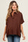 woman wearing a brown short sleeve button-up maternity top with a relaxed fit and styled with blue jeans