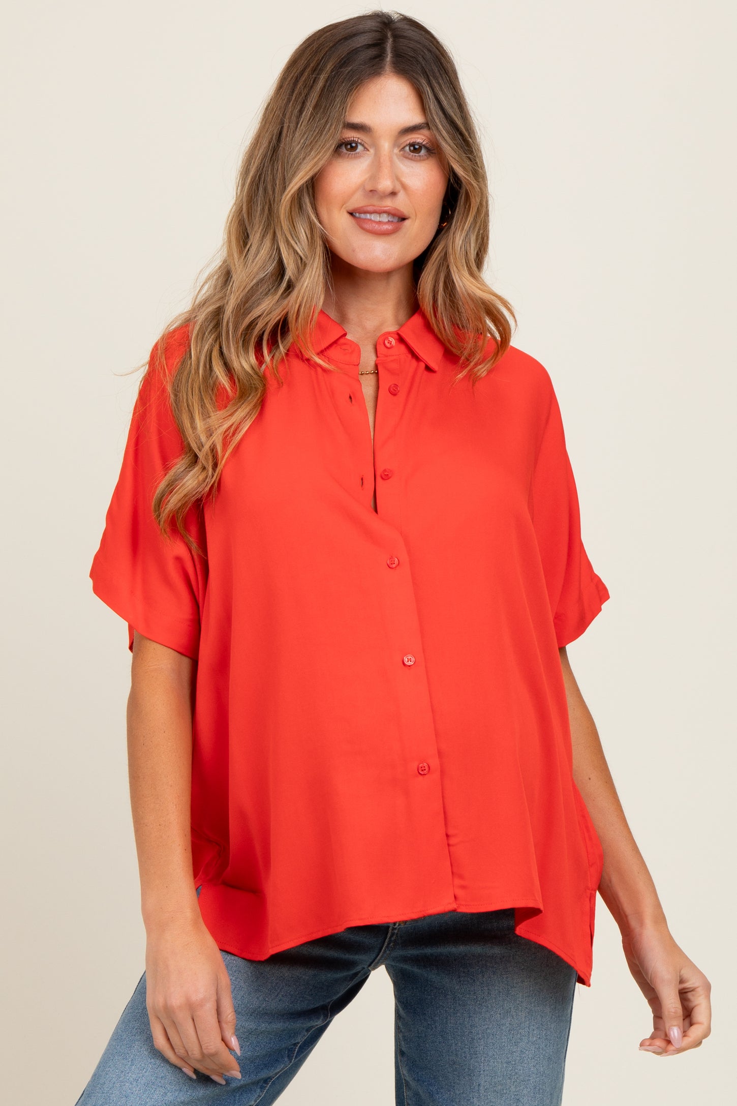woman wearing a bright red short sleeve maternity blouse with a button-down front and a relaxed fit