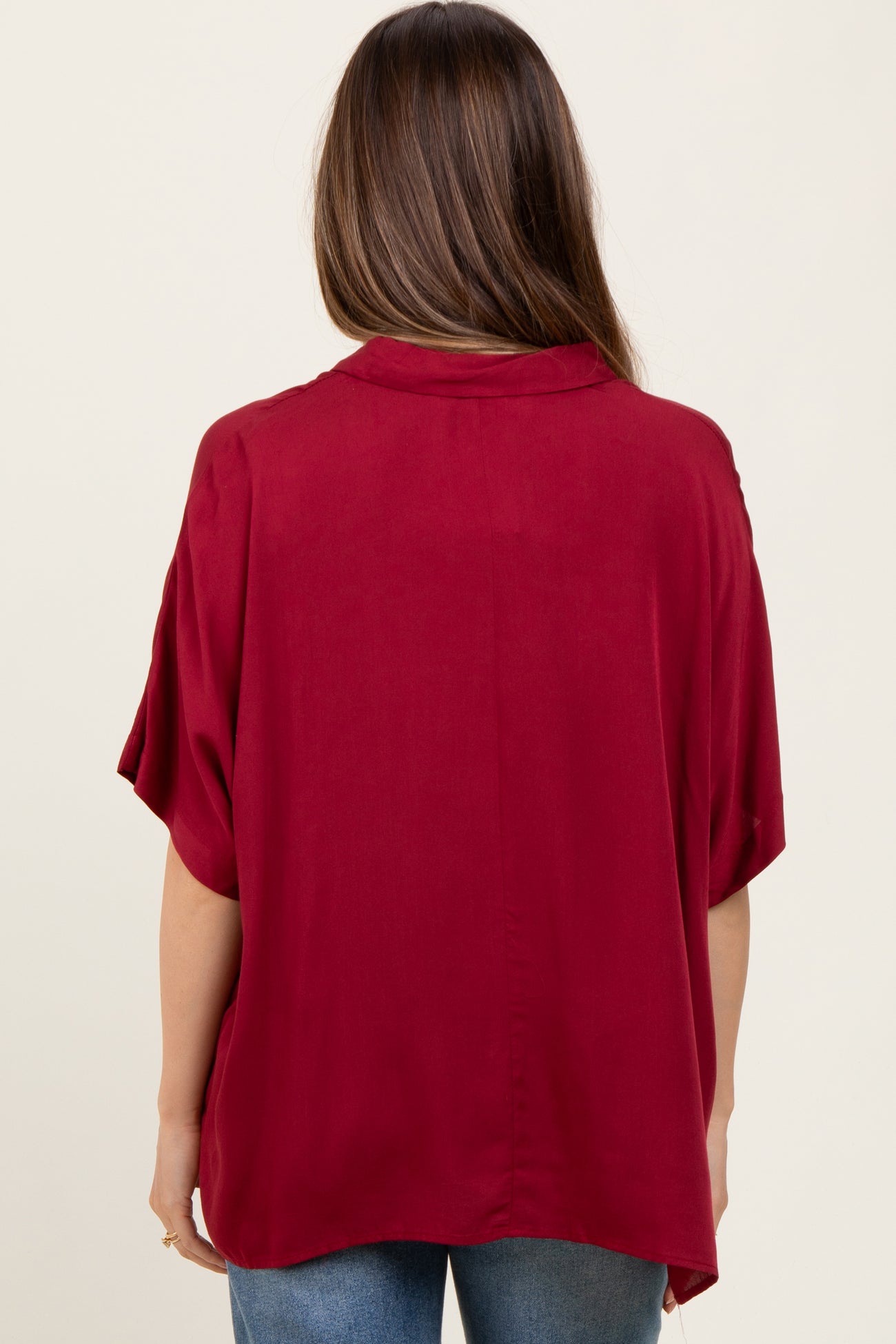 woman wearing a burgundy short sleeve maternity top, shown from the back with a relaxed fit
