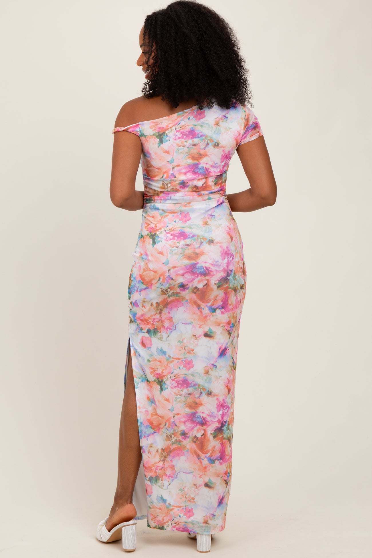 woman wearing a colorful off-shoulder maxi dress with a floral print and a side slit