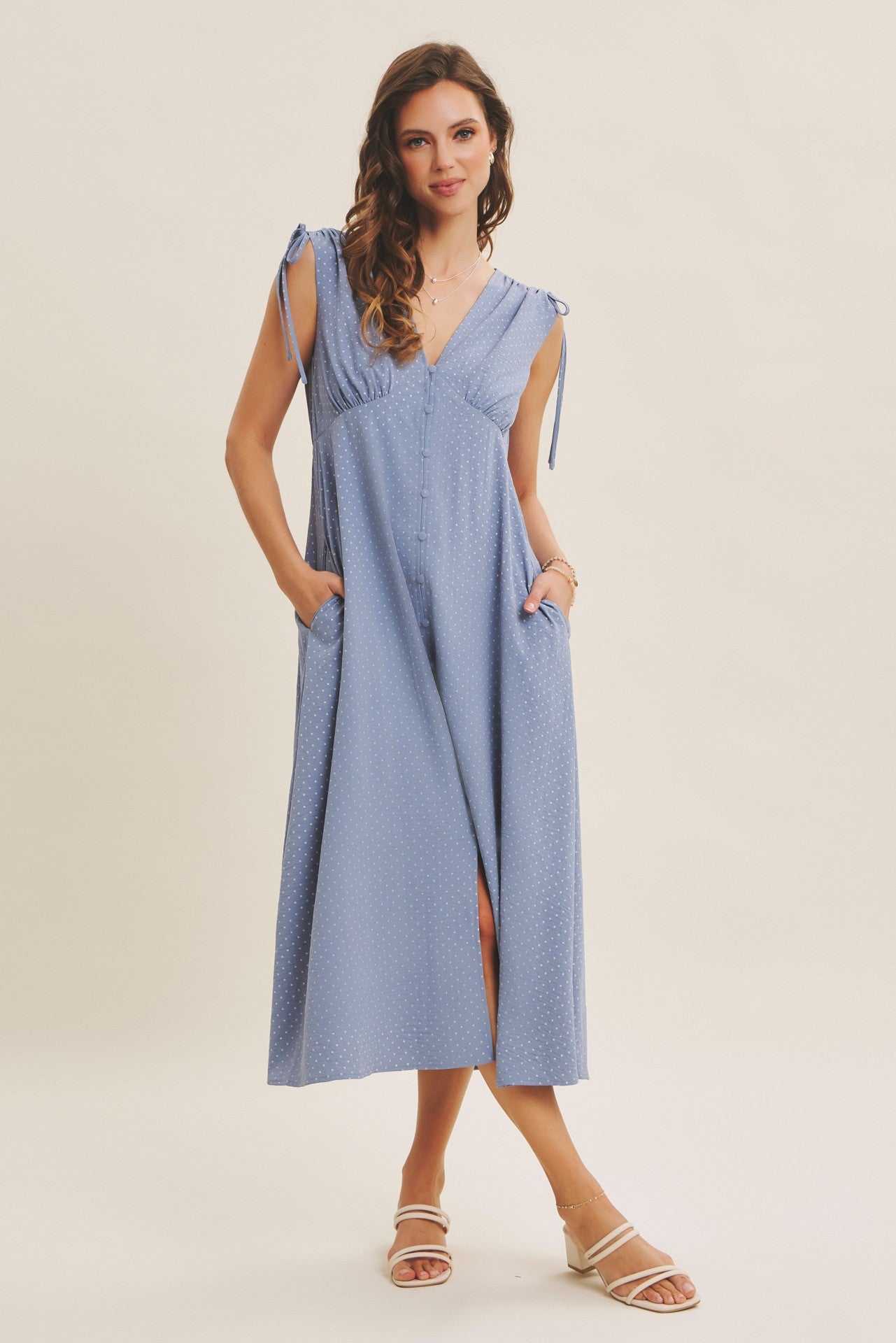 woman wearing a light blue sleeveless button-up midi dress with tie straps and pockets