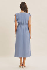woman wearing a light blue midi dress with tie sleeves and a gathered waist, viewed from the back