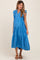 woman wearing a bright blue maternity dress with ruffled sleeves and a tiered skirt, showing her baby bump