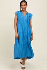 woman wearing a blue tiered midi dress with ruffle sleeves and a v-neckline, standing against a neutral background