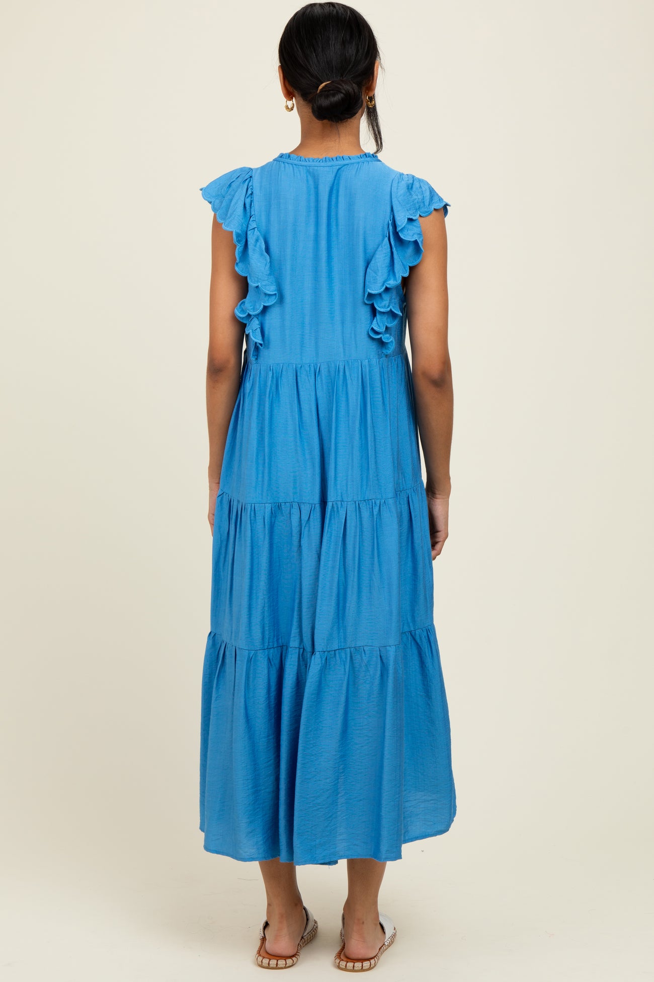woman wearing a blue tiered maxi dress with ruffle sleeves, viewed from the back