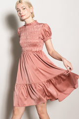woman wearing a dusty rose puff sleeve dress with a smocked bodice and a flared skirt