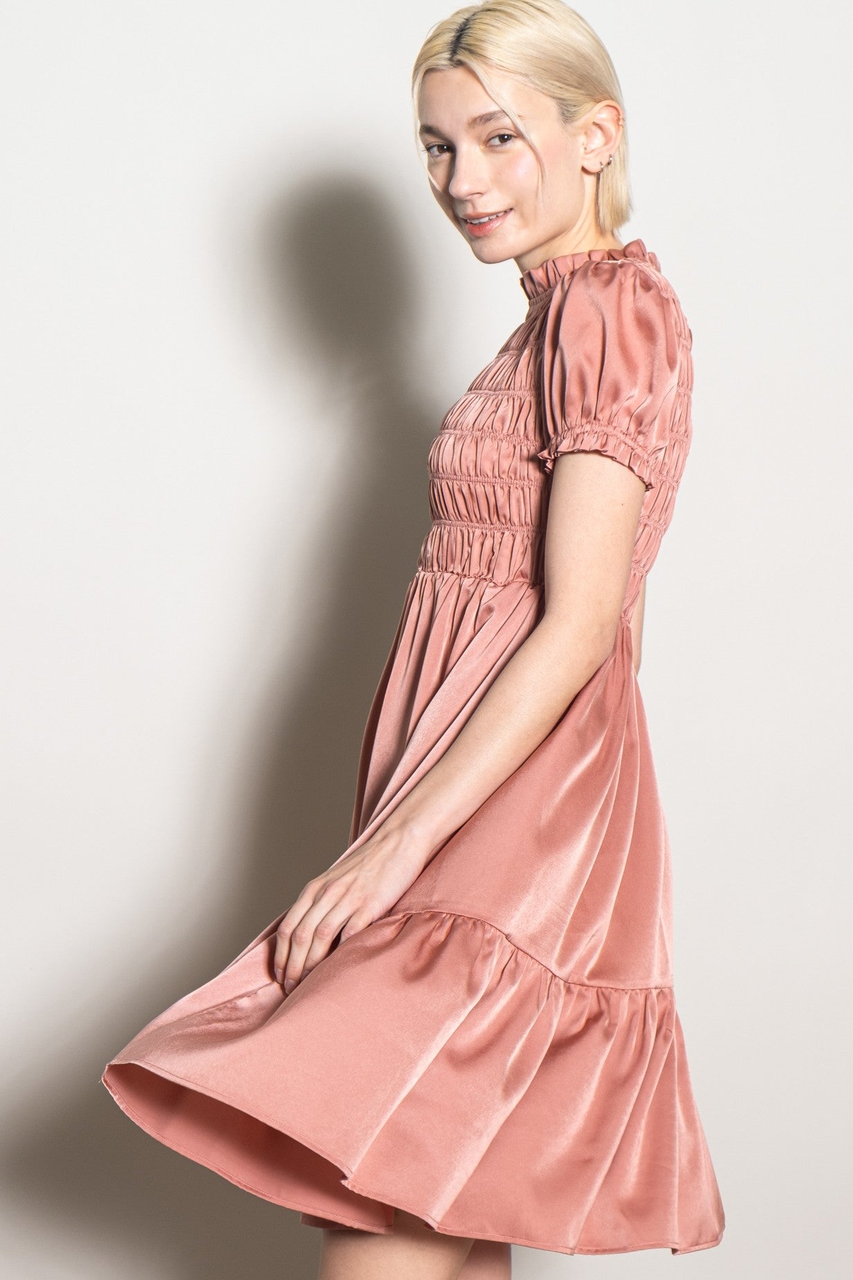 woman wearing a dusty rose short sleeve smocked dress with a ruffled hem and a fitted bodice
