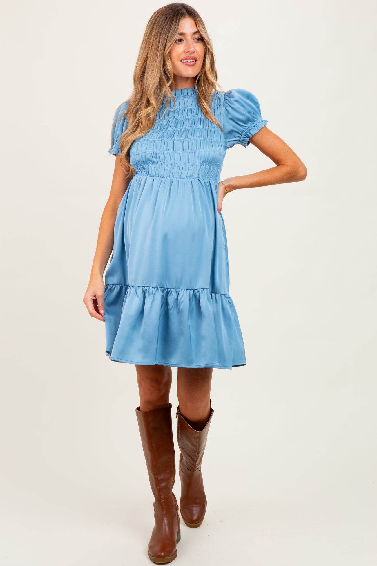woman wearing a light blue short sleeve maternity dress with smocking and a ruffled hem, showing her baby bump