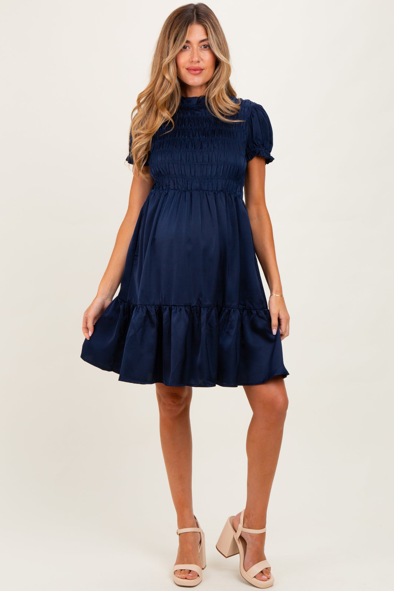 woman wearing a navy blue maternity dress with short puff sleeves and a ruffled hem, showing a baby bump