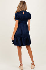 woman wearing a navy blue short sleeve maternity dress with a smocked bodice and tiered ruffle hem