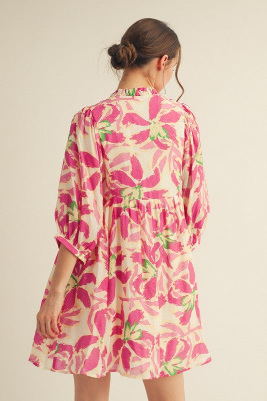 woman wearing a back view of a pink floral print dress with three-quarter sleeves and a gathered waistline