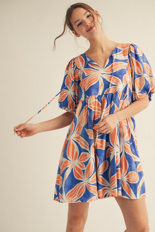 woman wearing a blue and orange floral print short sleeve dress with gathered detail and tie straps